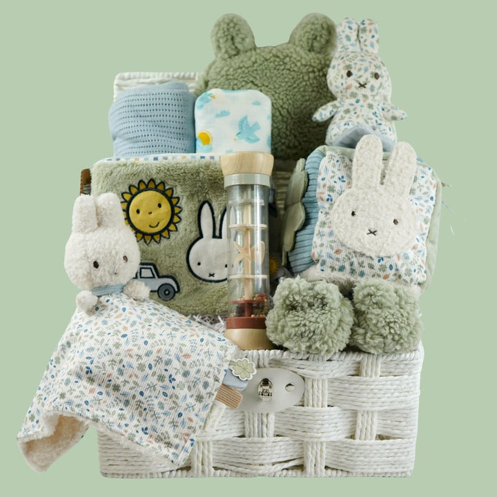 miffy themed baby hamper with green soft book, activity cube in pastel shades of green, white and blue, miffy soft rattle and matching comforter, rain rattle, blue cellular blanket, white muslin swaddle with bluebirds, fluffy green hat with ears and matching booties 