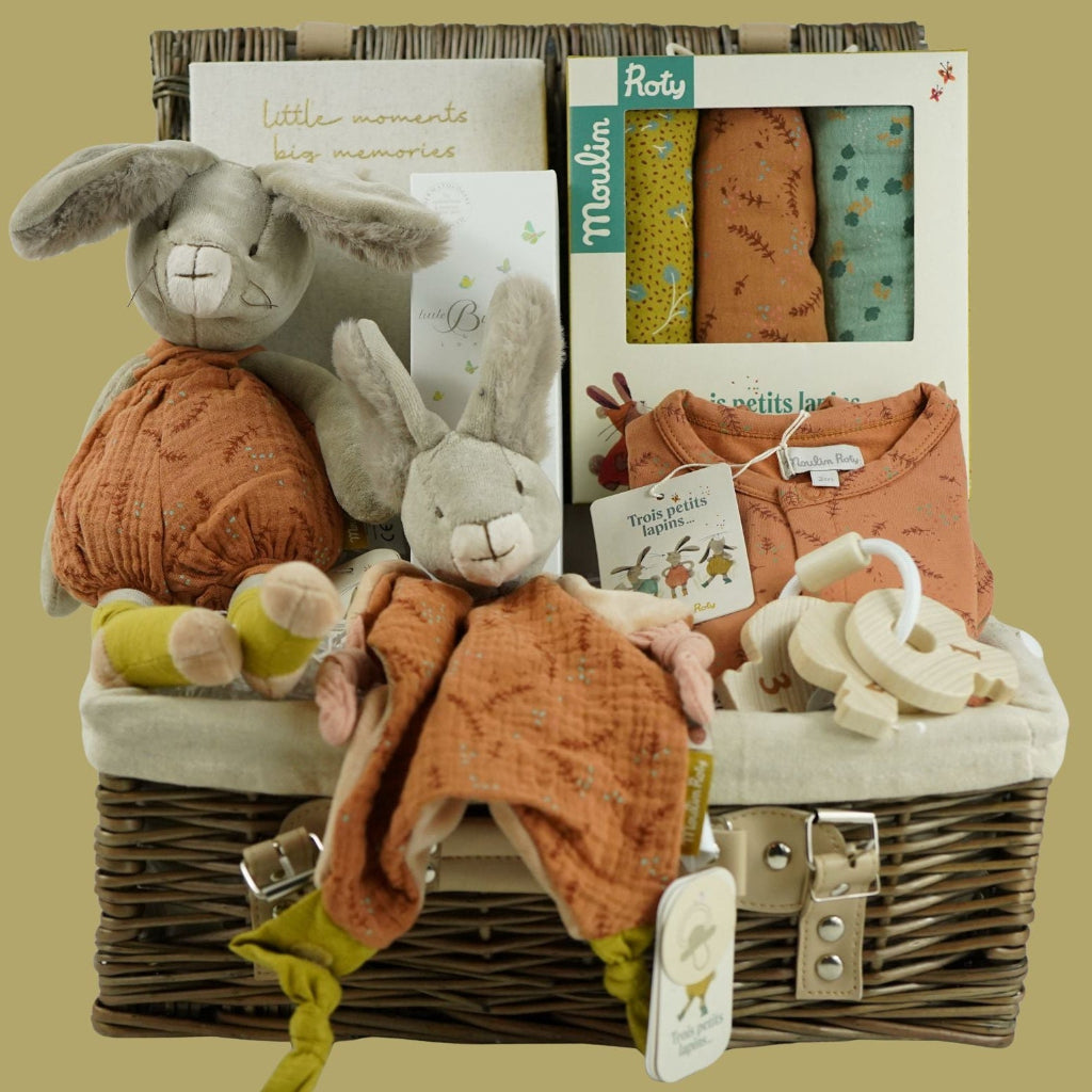 luxury neutral baby hamper  with Moulin Roty  3 lapins  soft toy and matching comforter, pack of 3 matching muslins and a sweet soft baby sleepsuit, baby organic bubbles and bunny milestone cards , wooden keys for teething all in  a wicker hamper basket