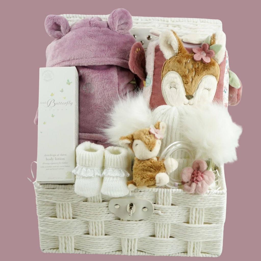 Baby gift basket with plush toys and accessories on a pink background