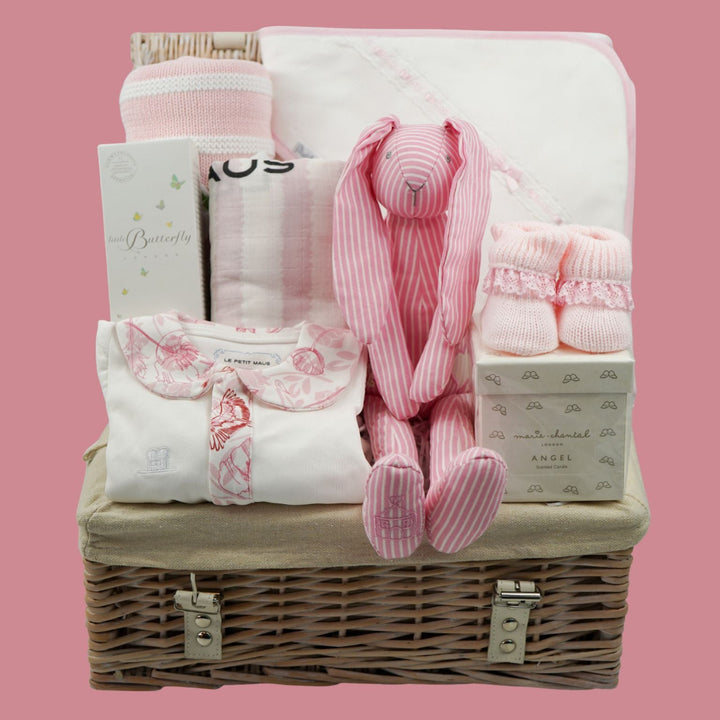 baby girl luxury hamper basket with organic baby sleepsuit with pink floral collar and trim, baby organic toiletries, cotton pink stipe baby blanket, pink stripe swaddle, white hooded towel with pink ribbon trim, pink booties, luxury candle for mum and pink stipe bunny soft toy rattle 