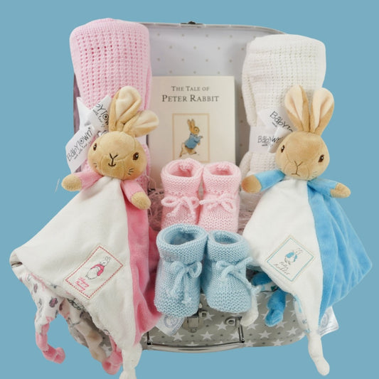 twin hamper with Beatrix potter flopsy bunny comforter in pink and white  ab=nd blue and white Peter Rabbit comforter, baby booties in pink and blue, Peter rabbit book, pink cellular blanket, white cellular blanket