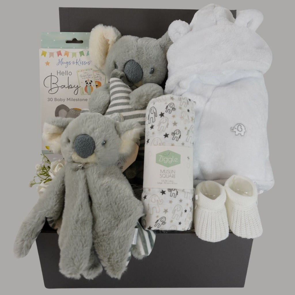 baby hamper box with white soft baby dressing gown in white with cute ears, Koala sofy comfort blanket in grey and white, baby milestone cards , muslin in white with grey elephants , white baby booties