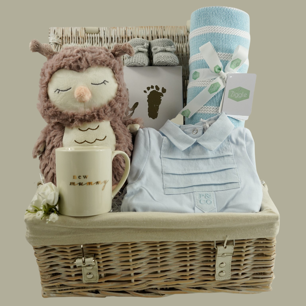 wicker basket, baby boy blue striped romper with a collar, Steiff owl soft toy, baby hand and footprint set, blue and white striped blanket, baby bootees, mummy mug