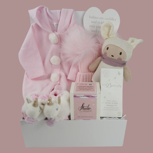 Pink baby hamper with Deolinda baby romper, baby unicorn slippers with a rattle, pink fluffy pom pom hat, baby organic toy, baby organic toiletries, hot chocolate bomb