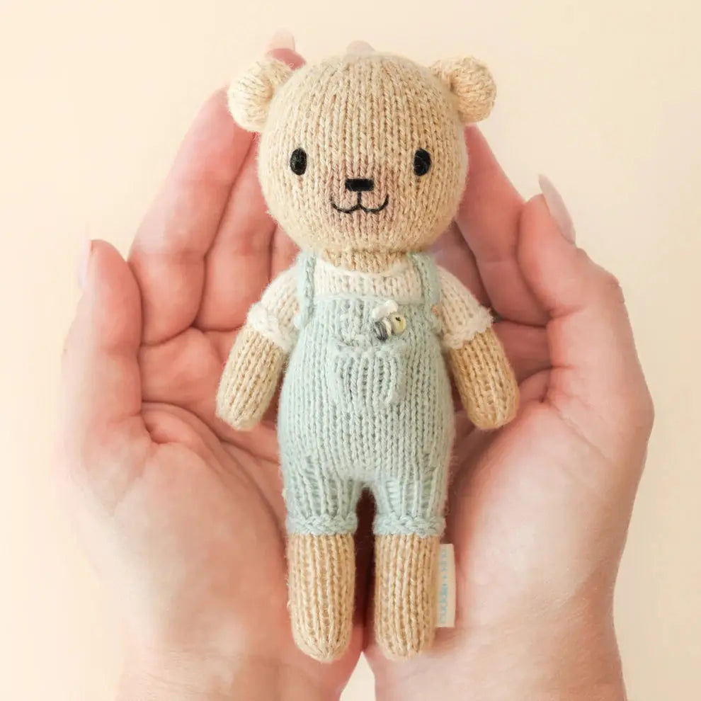 tiny charlie hand knitted bear in pale blue dungaree's with a honey bee