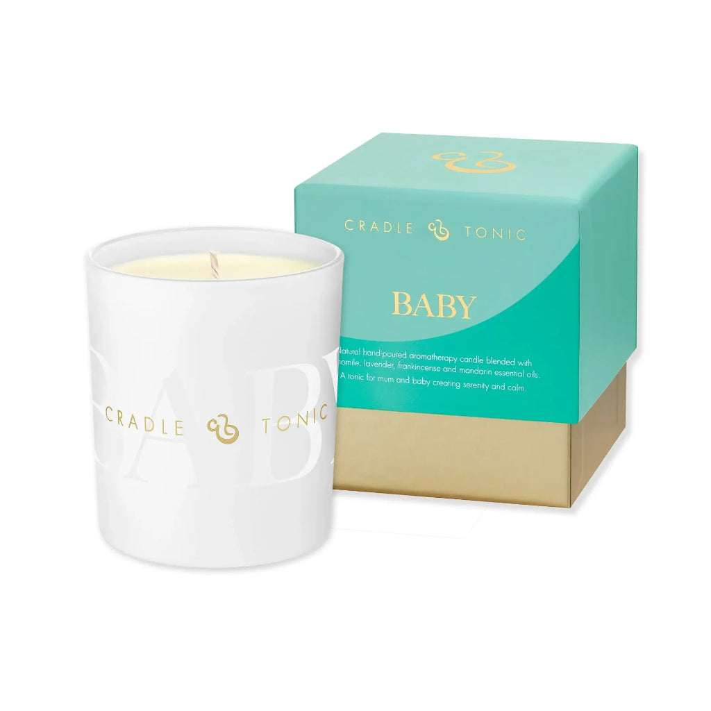 A white glass jar candle with a single wick and pale yellow wax, shown next to its mint green and gold Cradle of Tears Baby scented box on a white background.