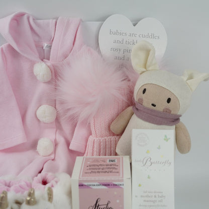Pink baby hamper with Deolinda baby romper, baby unicorn slippers with a rattle, pink fluffy pom pom hat, baby organic toy, baby organic toiletries, hot chocolate bomb