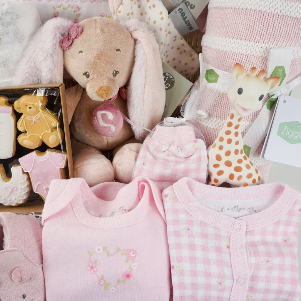 baby hamper basket with baby themed biscuits for mum, baby white muslin with bunnies, pink layette, musical baby bunny and matching comforter, baby pink shoes with cute ears , pink and white knit blanket