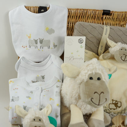 wicker hamper basket with white cotton baby clothing set with sheep design, organic baby blanket in buscuit colour, sheep soft toy, sheep rattle and sheep baby comforter finger puppet, wooden baby teether, organic baby wash
