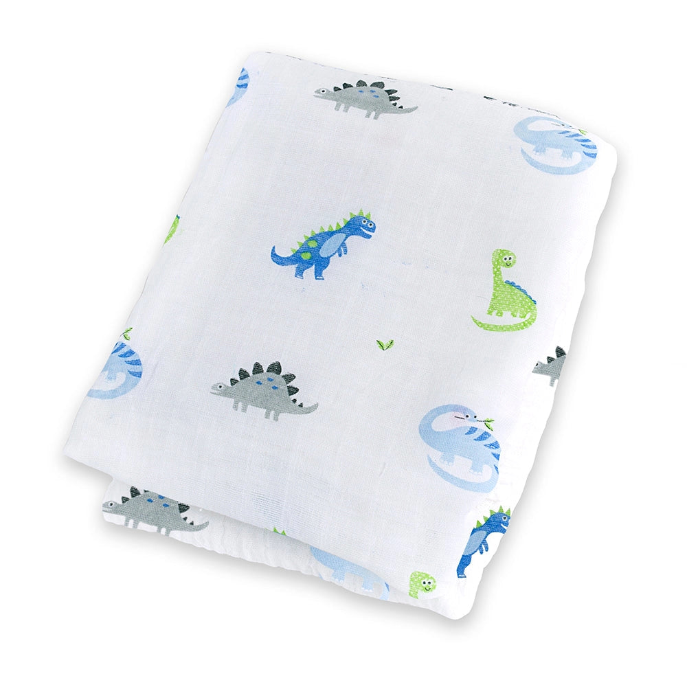 A folded white muslin blanket featuring a playful pattern of cartoon dinosaurs in blue, green, and gray, set against a plain white background.