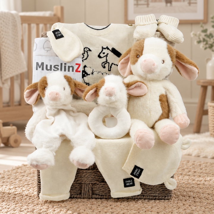 luxury baby hamper with Fable & Bear organic cotton baby set , muslins, co soft toy , cow comforter and rattle in a grey hamper basket