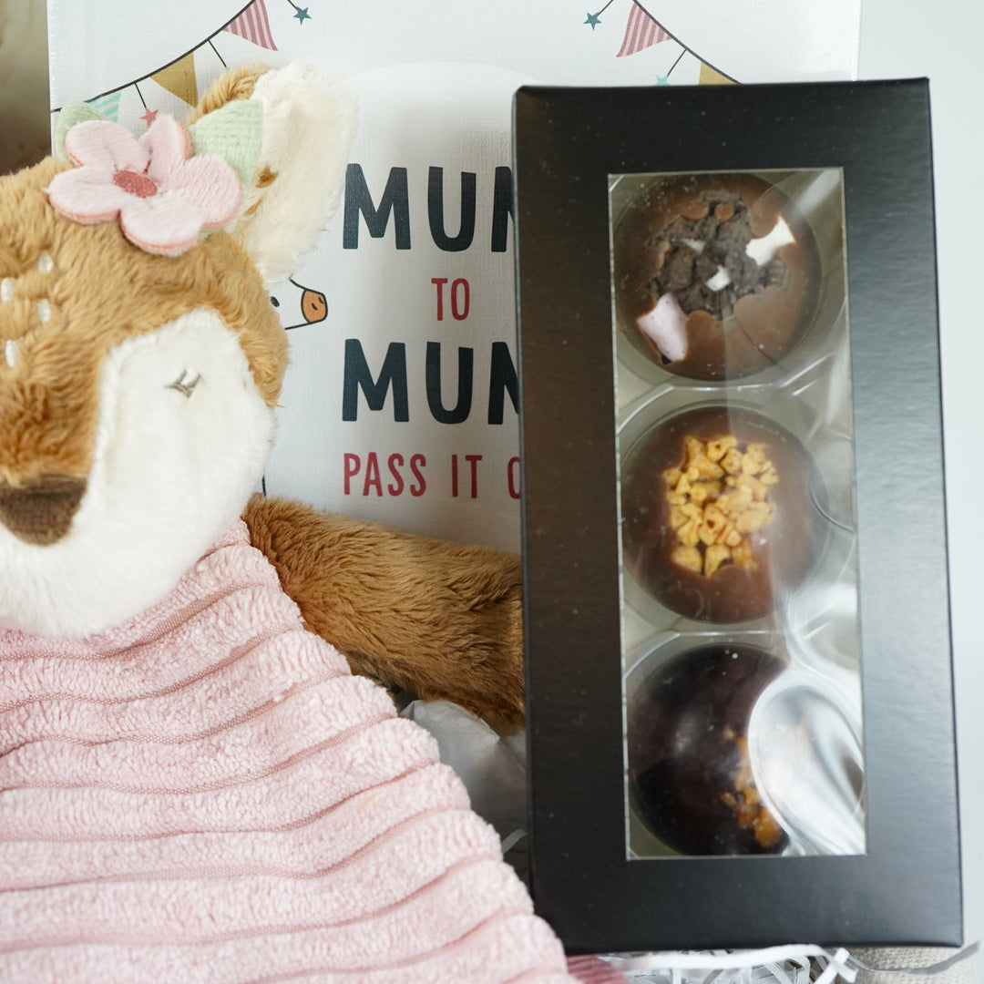 uxury mum and baby hamper, luxury pink velour sleepsuit with gold angel wings embroidery, pink star knit blanket, soft pink deer comforter,  ivory alpaca baby slippers, 4 sophie la giraffe muslins, box of chocolate domes, mum to mum tips book