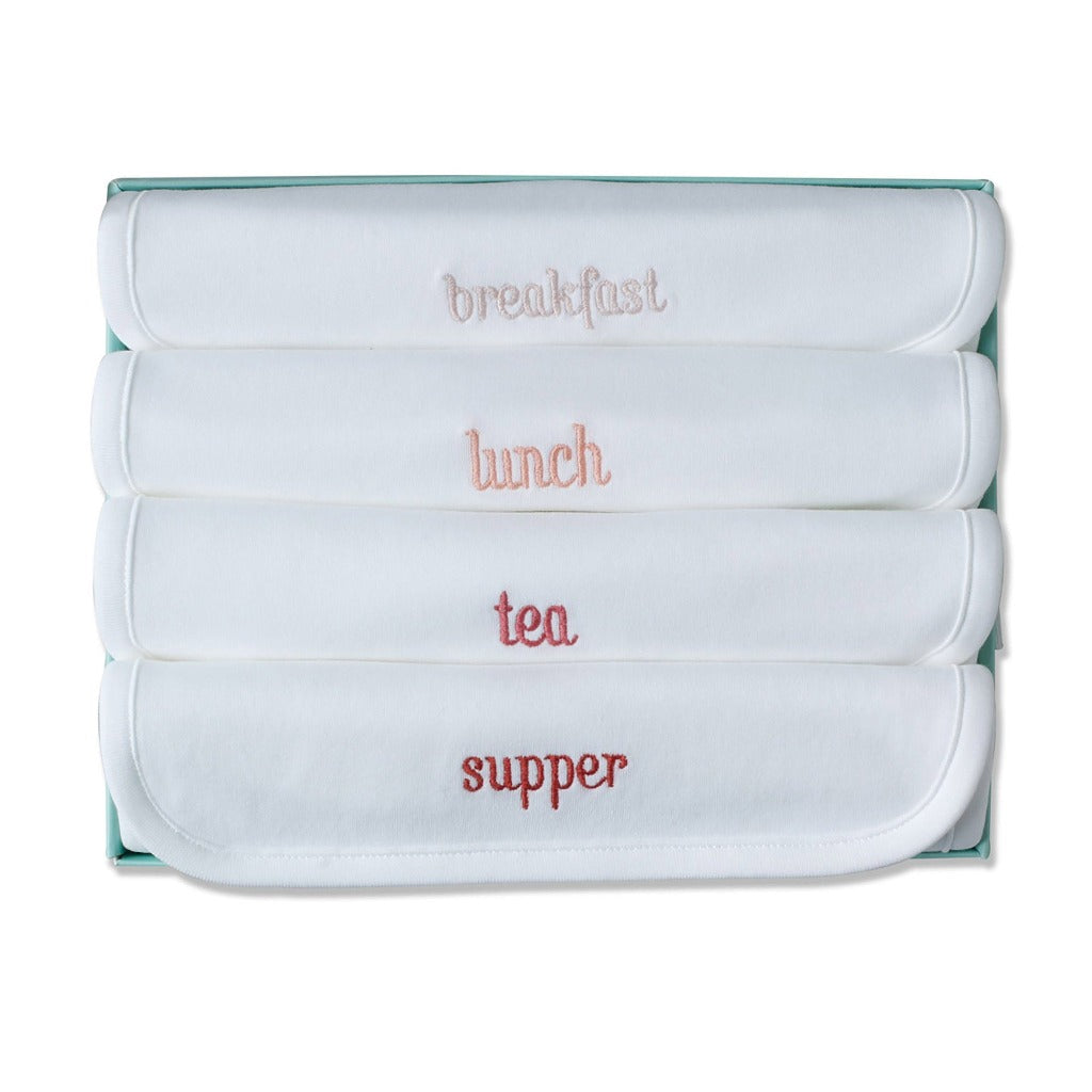 white luxury bibs with breakfast, lunch, tea and supper embroidered in terracotta colours in a gift box with a white drawstring bag with Marie Chantal emblem