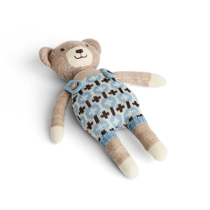 A plush teddy bear toy wearing a light blue knit romper with a brown and white pattern, made from merino wool 