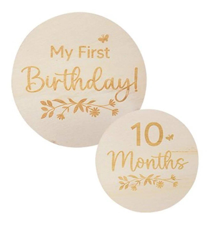 Two round wooden baby milestone plaques on a white background, one engraved with 'My First Birthday!' and the other with '10 Months'.