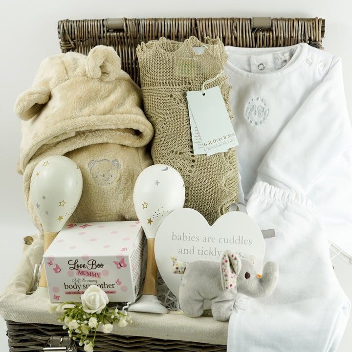 neutral baby gift in wicker hamper basket, baby dressing gown with ears, white designer baby outfit, baby maracs, mummy toiletries, steiff elephant rattle, G H Hurt baby shawl