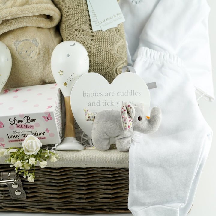 neutral baby gift in wicker hamper basket, baby dressing gown with ears, white designer baby outfit, baby maracs, mummy toiletries, steiff elephant rattle, G H Hurt baby shawl