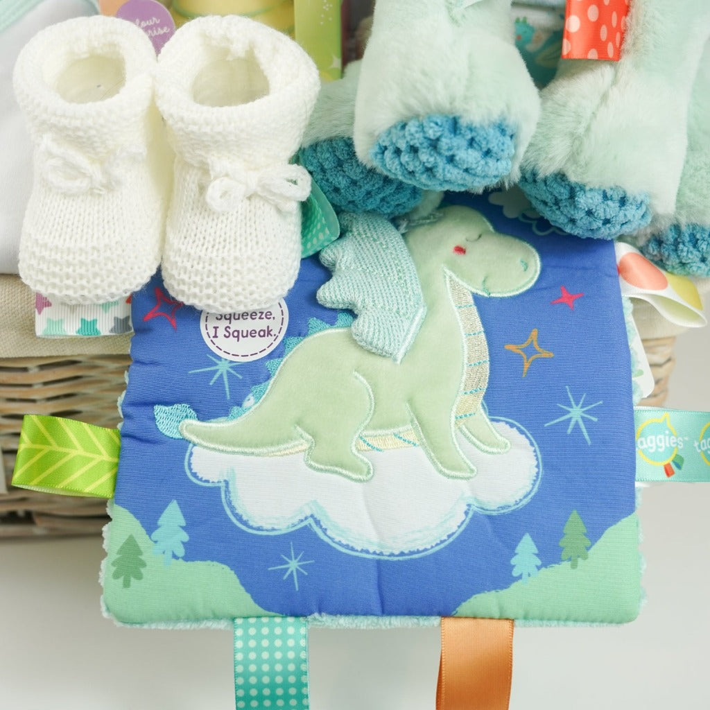 baby hamper basket, baby journal, baby layette outfit in pale mint green with elephants , white baby dressing gown with cute ears, white hot chocolate bomb, baby organic bubble bath, Dragon taggie in green and matching taggie book , white knit booties