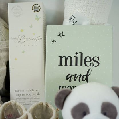 Neutral Baby hamper, baby organic cream outfit with hat, baby leggings and wrap over baby bodysuit, organic toiletries, knit booties, white blanket, miles and moments cards , panda comforter