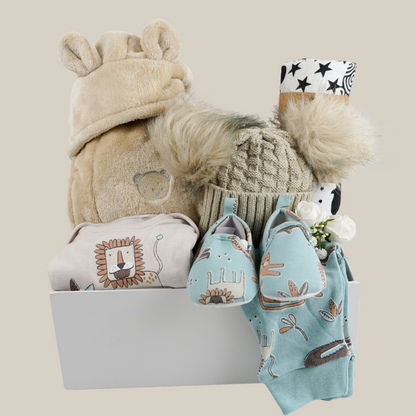 baby hamper gift with caramel coloured baby dressing gown with cute ears, caramel double pom pom baby hat, baby clothing set with bodysuit with a lion and turqouise baby trouses with lion design and matching baby shoes, sensory muslin swaddle in black and white 