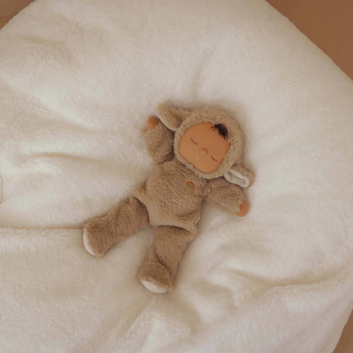 Stuffed toy in a brown outfit lying on a soft white surface