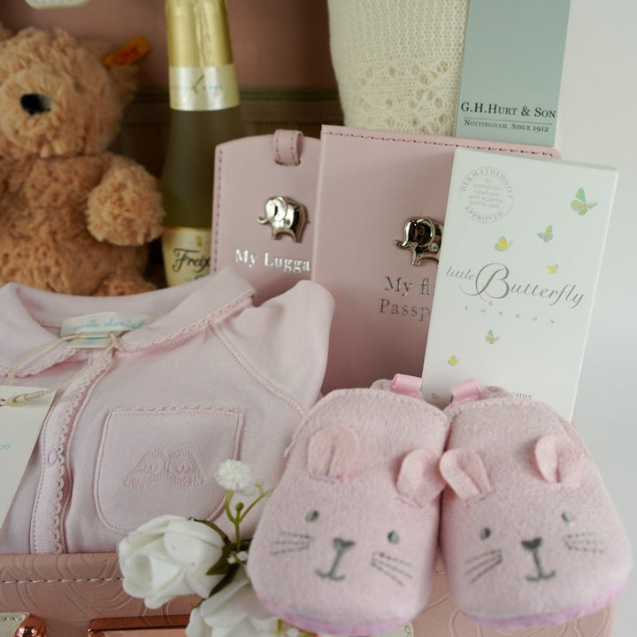 Pink baby suitcase with Steiff teddy, cashmere shawl, baby passport and luggage label, Marie Chantal pink baby sleepsuit, pink baby slippers with bunny ears , Butterfly London baby massage oil