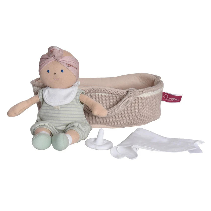 soft doll in green outfit with a dummy and sheet in a baby knitted basked 