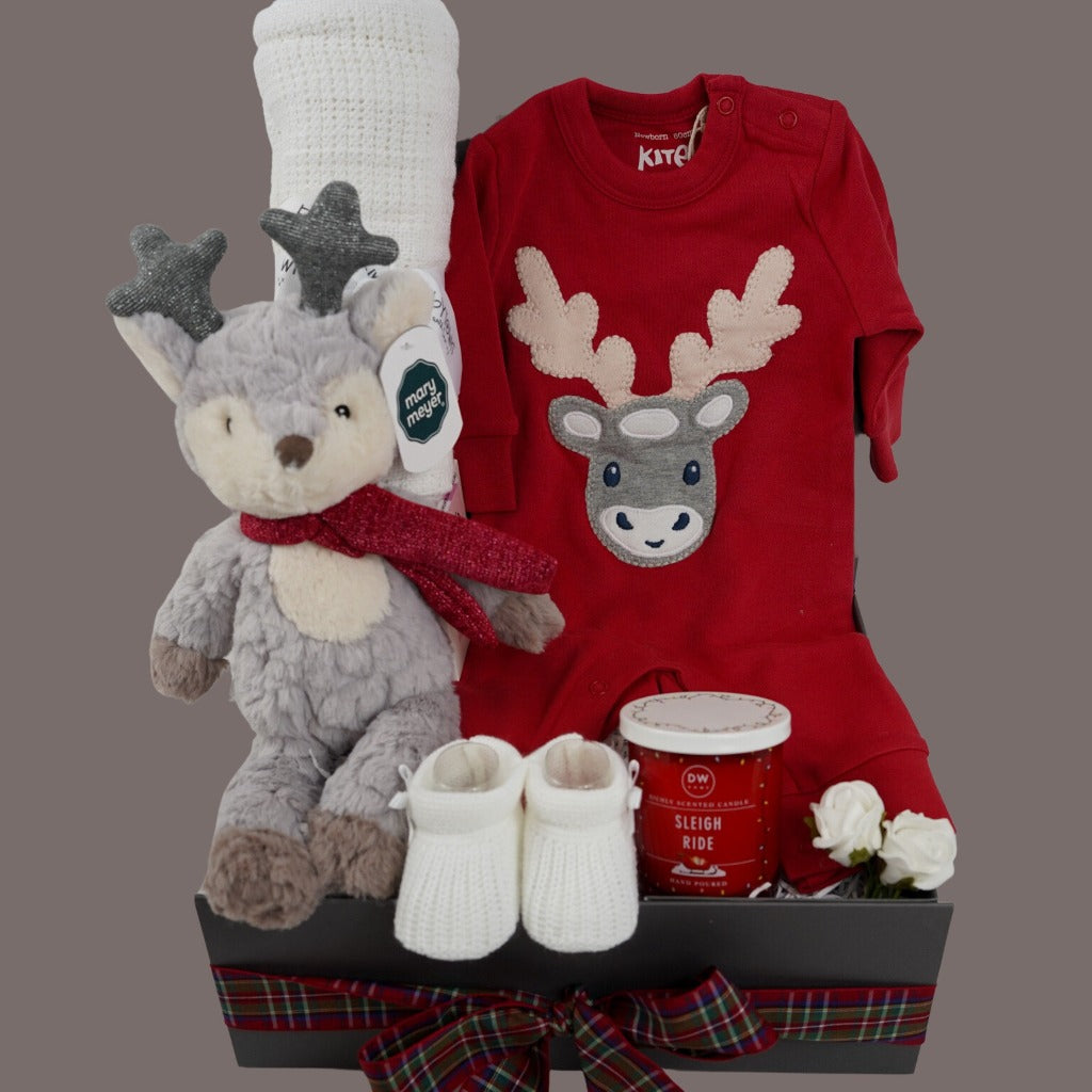 Christmas baby hamper, organic cotton red  baby sleepsuit with applique reindeer, reindeer soft toy in grey and cream with a red scarft and glittery antlers, white cotton cellular baby blanket, white knit baby booties, red Christmas candle