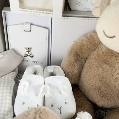 Neutral Baby hamper with monkey soft toy, monkey baby comforter, baby booties, baby's first passport holder and luggage label in white with a silver teddy, clay footprint hanger, baby star wooden teether, spanish style baby sleepsuit