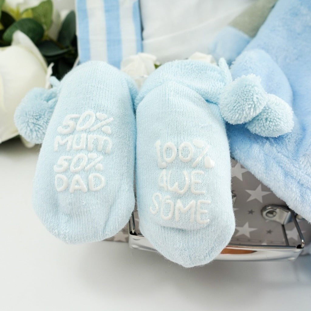 cute blue baby socks with pom poms and writing on the sole 