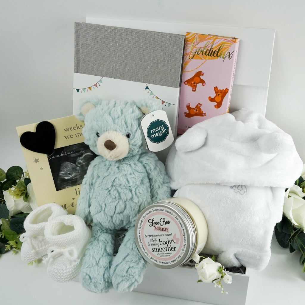 antenatal pregnancy hamper with baby scan photo frame , pale blue/green soft baby teddy, pregnancy and first year of life journal in a grey cover, cute white baby dressing gown with cute ears, white knit baby booties, fairy tale inspired chocolate