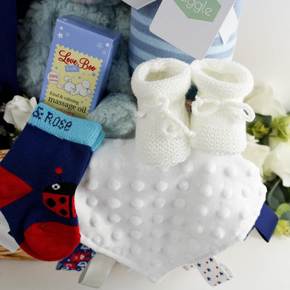 Willow baby hamper basket, ladybug baby leggings, ladybug baby long sleeve tshirt, pale blue soft mary meyer teddy bear, white double pom pom fluffy hat, ziggle blue reversible baby blanket with stars, soft white knit booties, baby taggie comforter, ladybug sock by blade and rose, baby massage oil