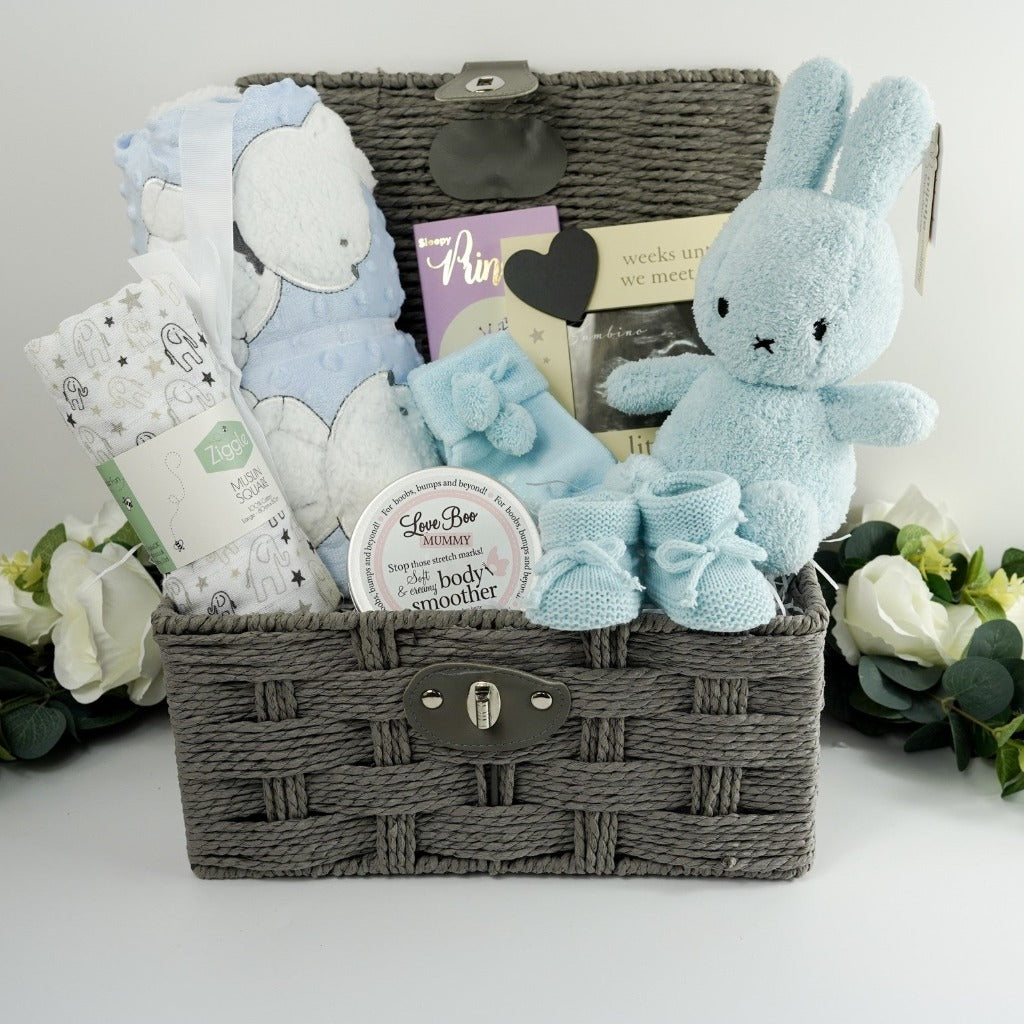 Grey hamper basket, white and grey baby muslin with elephants, Love boo mummy body butter , boutique luxury chocolate bar, pale blue miffy bunny rabbit, blue knit baby booties, pregnancy countdown frame with chalk board heart, pale blue soft sherpa backed baby blanket with applique bunny and teddy