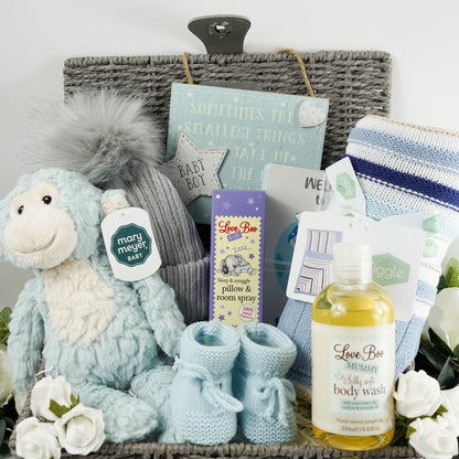 Grey baby hamper basket with soft blue and white monkey by Mary Meyer, grey pom pom baby hat, baby blue knit booties, baby boy room plaque with writing, Ziggle blue stipe heavy knit blanket, Love Boo pillow spray , Love boo mummy body wash