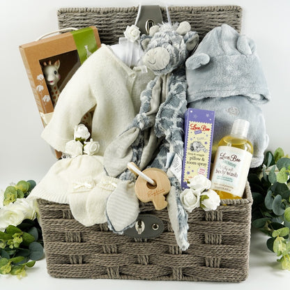 Grey hamper basket with baby gift items including  soft white baby cashmere cardigan, soft white baby cashmere baby hat, soft cashmere baby mittens with a bow, sophie la giraffe baby toy and teething toy, grey soft fleece baby dressing gown with ears, grey soft elephant blanket comforter with knot ends, baby pillow and room spray by Love boo, mum silky wash by Love boo, wooden key shaped teether 