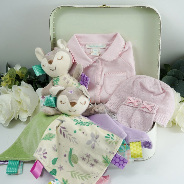 Marie Chantal baby gift suitcase in pale green with Marie Chantal logo, pink picot edge baby sleepsuit with angel wings embroidered on the pocket, pink cashmere baby hat and mittens by GH Hurt, soft floral fawn taggie blanket by Mary meyer and matching fawn floral rattle