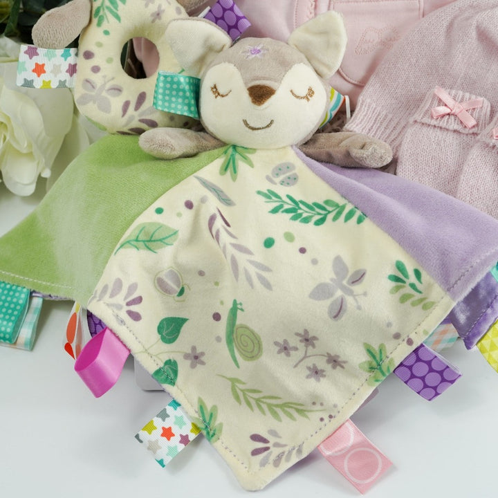 Marie Chantal baby gift suitcase in pale green with Marie Chantal logo, pink picot edge baby sleepsuit with angel wings embroidered on the pocket, pink cashmere baby hat and mittens by GH Hurt, soft floral fawn taggie blanket by Mary meyer and matching fawn floral rattle