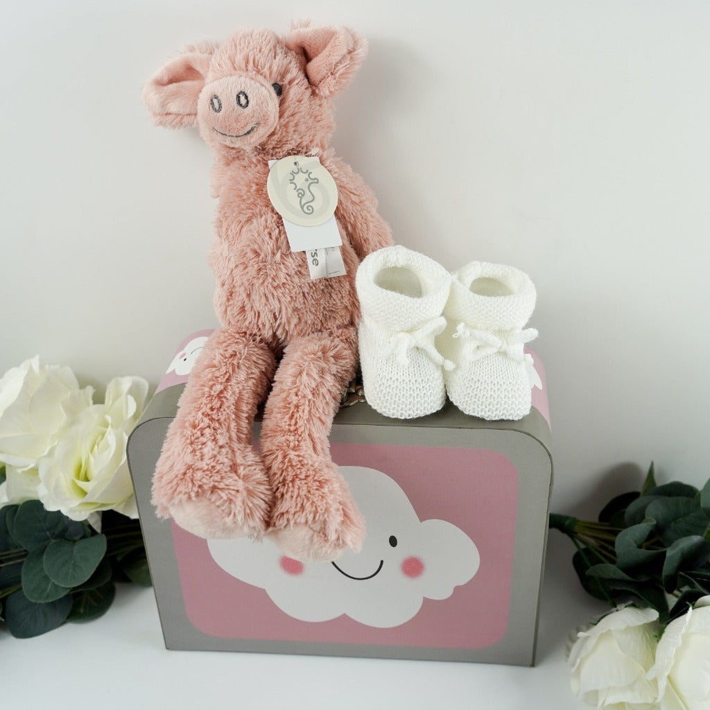 pink baby gift case with white clouds includes a soft pink pig by Happy Horse, soft white knit baby booties with a tie, soft white socks with writing on the sole, white cotton baby hat with two knotted corners, Love boo room and pillow spray, love boo baby wash