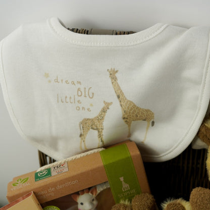 Luxury wicker hamper basket filled with baby gifts including baby clothing set in cream with a giraffe , includes baby sleepsuit, baby vest, baby bib, baby mittens, baby hat, Sophie La Giraffe So Pure rubber teething toy boxed, soft cream baby blanket with giraffe, giraffe soft toy, giraffe comforter, giraffe rattle ring toy, luxury gingerbread toffe chocolate in luxury wrapper, baby knit booties in white with tie, memorable moments baby cards with pastel animals