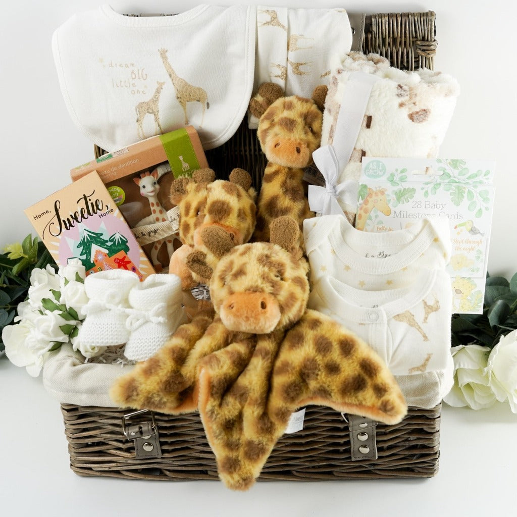 Luxury wicker hamper basket filled with baby gifts including baby clothing set in cream with a giraffe , includes baby sleepsuit, baby vest, baby bib, baby mittens, baby hat, Sophie La Giraffe  So  Pure rubber teething toy boxed,  soft cream baby blanket with giraffe, giraffe soft toy, giraffe comforter, giraffe rattle ring toy, luxury gingerbread toffe chocolate in luxury wrapper, baby knit booties in white with tie, memorable moments baby cards with pastel animals 