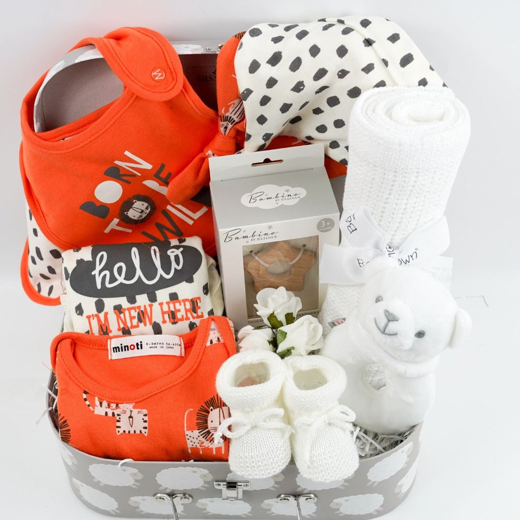 Baby suitcase with 2 bodysuits one orange one cream and grey with matching knot baby hats and bibs, white knit booties, wooden star shaped baby teether, white cotton cellular blanket, white bear rattle 