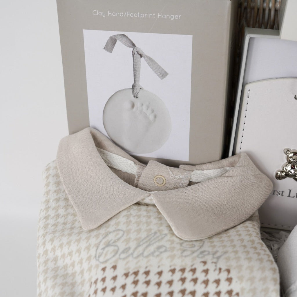 Neutral Baby hamper with monkey soft toy, monkey baby comforter, baby booties, baby's first passport holder and luggage label in white with a silver teddy, clay footprint hanger, baby star wooden teether, spanish style baby sleepsuit