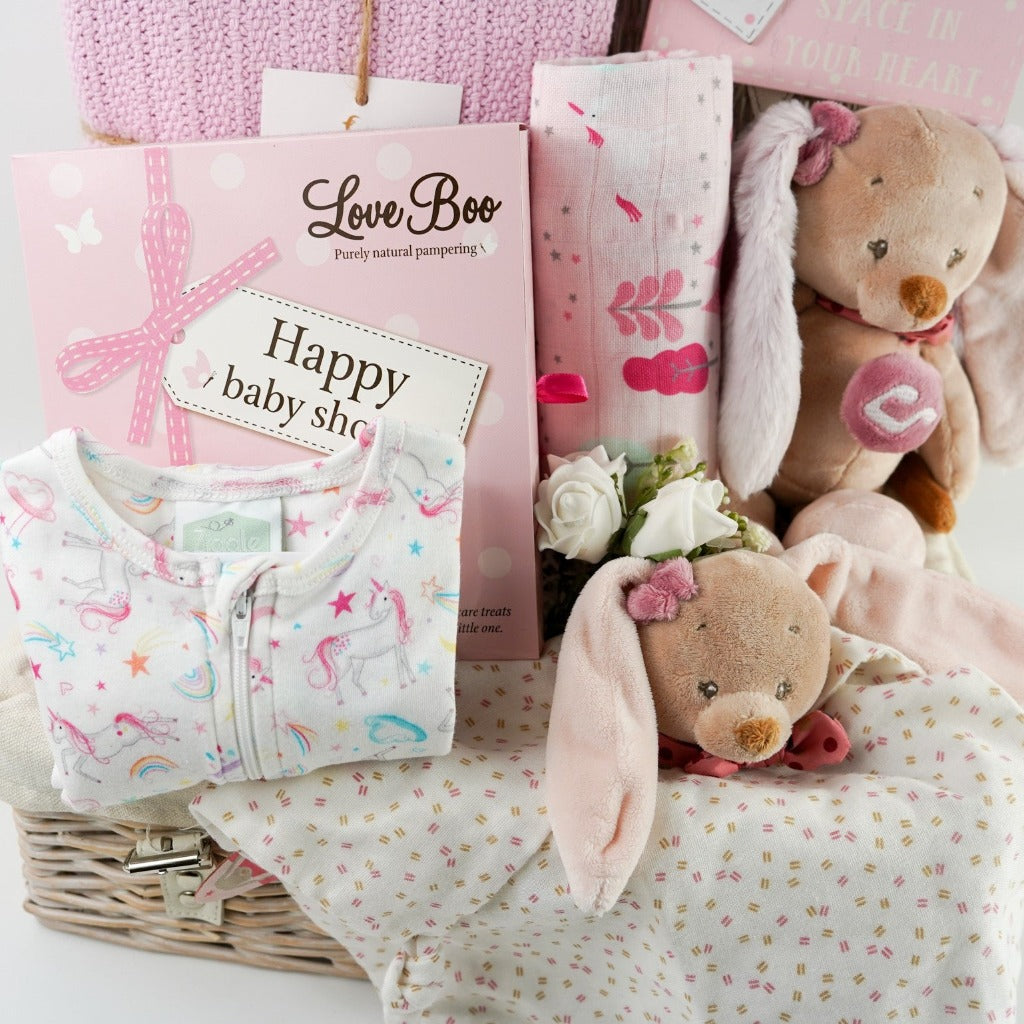 Pink themed baby shower gift hamper , baby zip up sleepsuit with unicorns in pink and white , natural baby toiletries , patel taupe rabbit with pink eats musical and matching rabbit baby comforter , unicorn pink muslin , pink heavy weight baby cellular blanket , nursery plaque