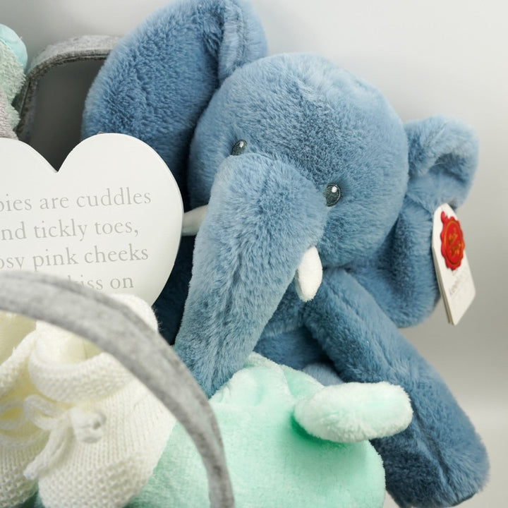 nappy caddy with baby gifts including a mint green baby dressing gown, mint green lion face hooded baby towel, baby blanket grey and white, muslin, soft cuddly ecofriendly elephant in blue and matching comforter, pregnancy toiletries