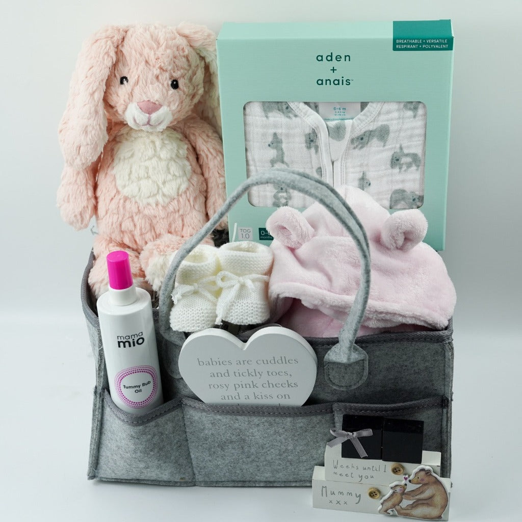 grey nappy caddy full of  pregnancy gifts including mum to be tummy rub oil, musical pink rabbit, baby pink dressing gown, baby white sleeping bag with grey koalas. pregnancy countdown plaque, baby bootees