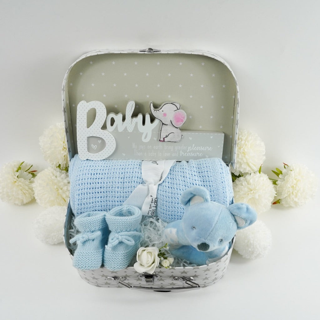 Soft blue baby gifts in a hamper case, blanket, teddy rattle, bootees and a nursery palque 