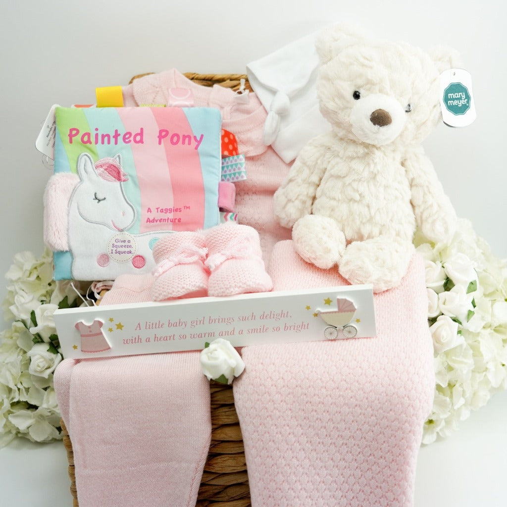 Baby girl gift hamper with pink fine knitted top and bottoms with frilled neck and scalloped edge, pink baby knitted shawl, pink soft taggie baby book, soft white teddy 