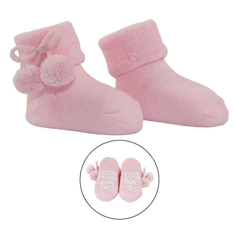 Pink baby socks with pom poms and writing on the sole