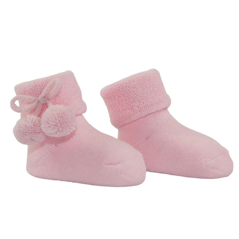Pink baby socks with pom poms and writing on the sole