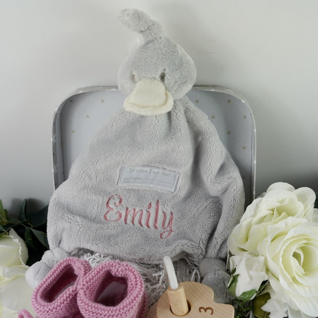 Small baby case with soft grey duck comforter, dusky pink knitted booties, wooden keys on a rope for teething